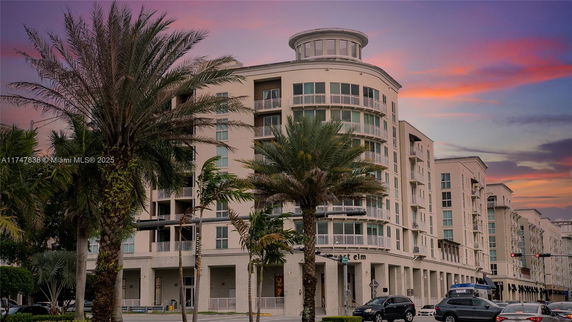 Front view of a multi-story building with rounded corner and balconies.