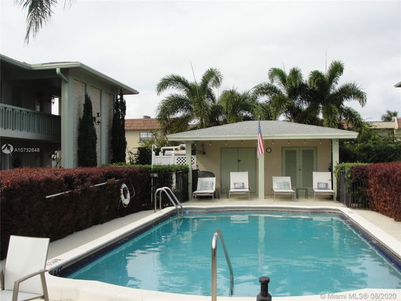 Outdoor swimming pool area with lounge chairs and surrounding buildings.