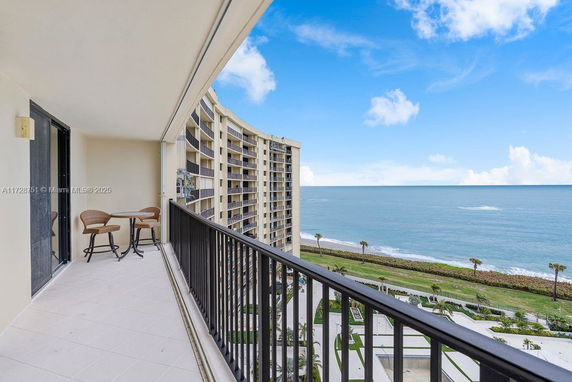 Balcony view overlooking the ocean with nearby high-rise buildings.
