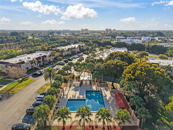 Aerial view showing a residential area with a swimming pool and surrounding greenery.