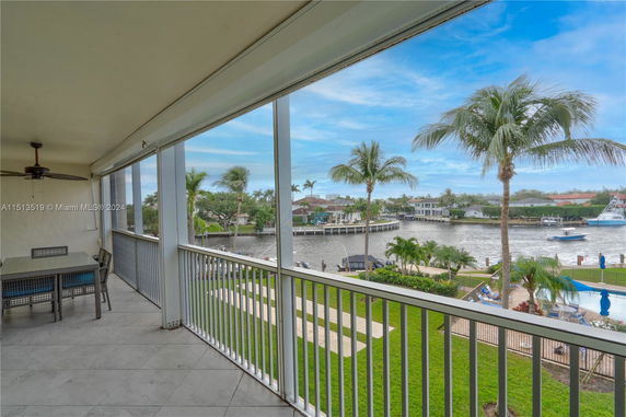 Outdoor balcony with a view of a waterfront and palm trees.