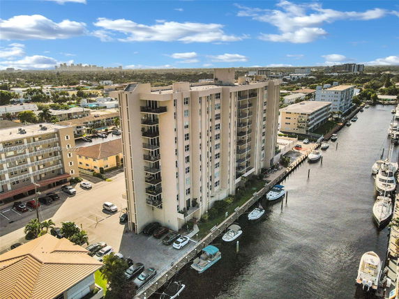 Aerial view of a waterfront apartment building with nearby canal and boats.