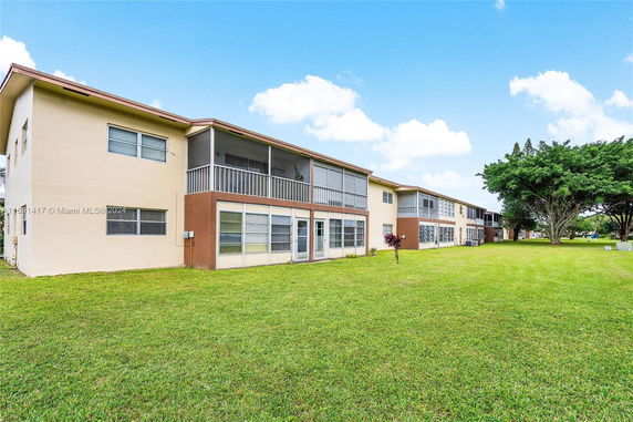 Side view of a multi-story residential building with screened balconies and glass windows.