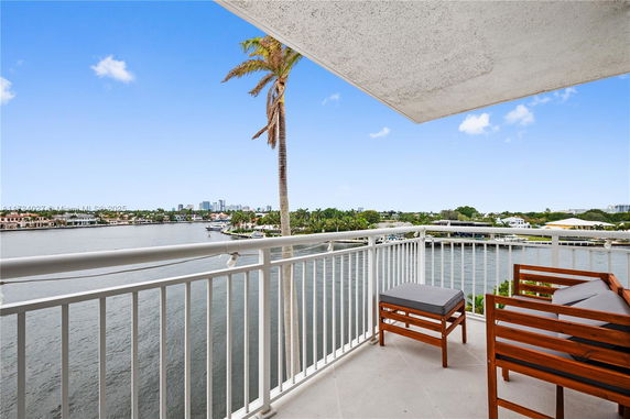 Balcony view overlooking a body of water with buildings and greenery in the distance.