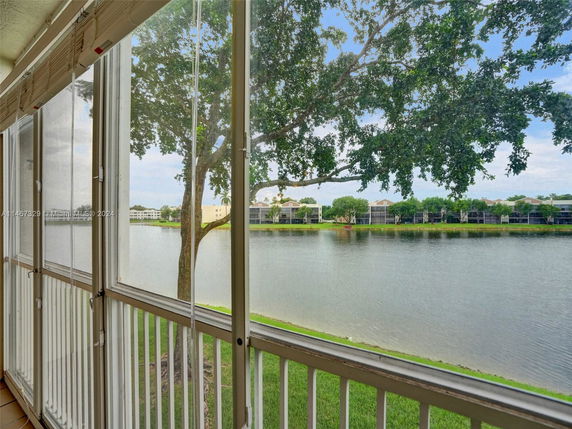 View from a balcony overlooking a lake with residential buildings across the water.