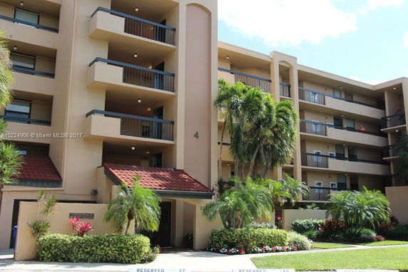 Front view of a multi-story residential building with balconies and a red tiled roof entrance.
