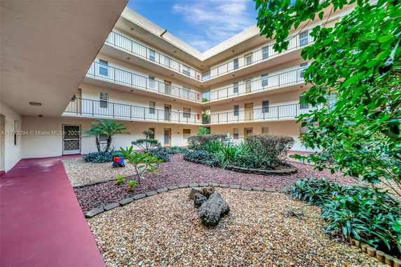 Courtyard of a multi-story apartment building with balconies and landscaped gardens.