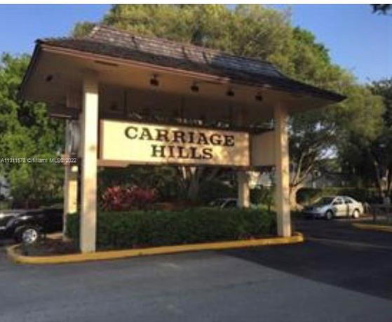 Front view of a sign for Carriage Hills at the entrance to a residential area.