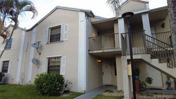 Front view of a two-story building with outdoor staircases and balcony.