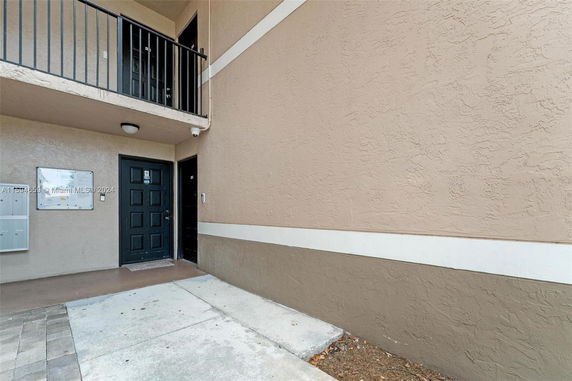 Entrance to a multi-story building with beige walls and black doors.
