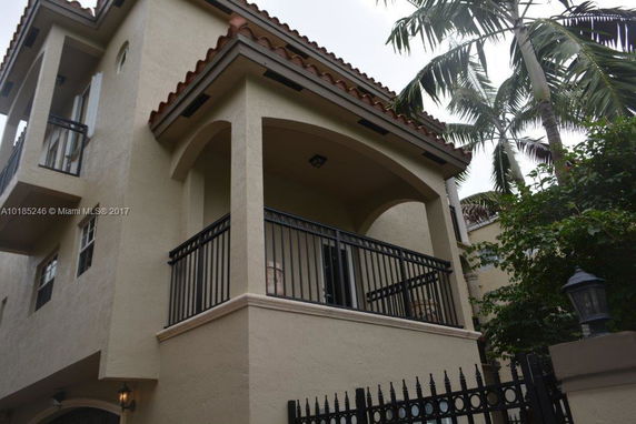 Front view of a multi-story house with arched balcony and decorative railings.
