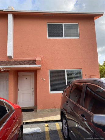 Front view of a two-story house with a pink exterior and a white door.