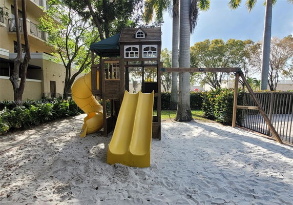 Outdoor playground with yellow slides and a wooden play structure.