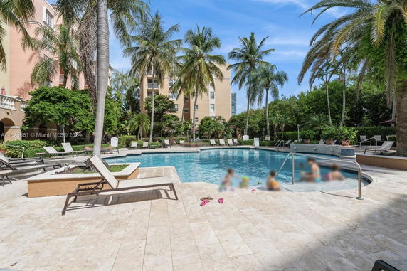 Outdoor swimming pool with lounge chairs and palm trees surrounding it.