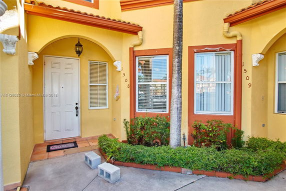 Front view of a two-story house with an arched entryway and decorative windows.