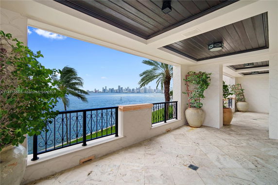 Covered terrace with a view of a city skyline across the water.