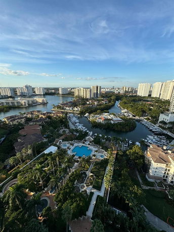 Aerial view of a waterfront residential area with high-rise buildings, greenery, and waterways.