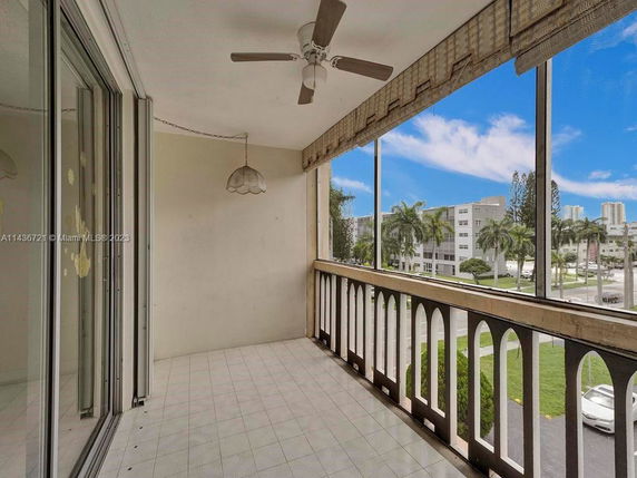 Balcony view from a building overlooking surrounding area with buildings and palm trees.