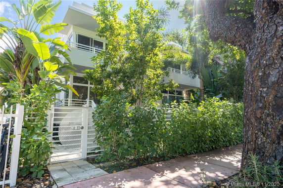 Front view of a modern two-story house with large windows and a gated entrance.