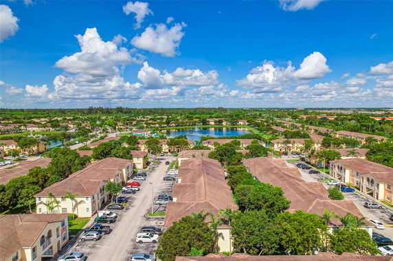 Panoramic view of residential area with multiple buildings, roads, and a pond.