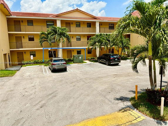 Front view of a multi-story apartment building with a parking area in front.
