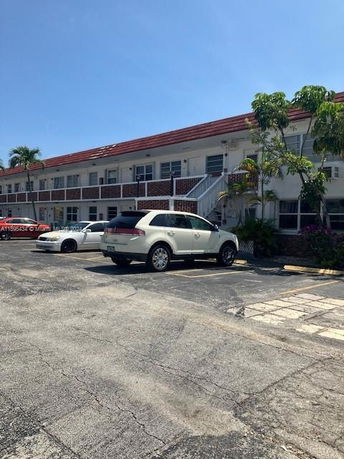 Front view of a two-story building with vehicles parked in front.