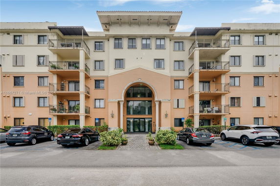 Front view of a multi-story residential building with balconies and an arched entrance.