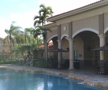 Outdoor swimming pool adjacent to a building with columns and arches.