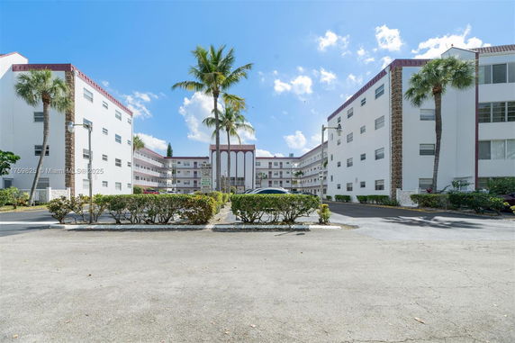 Front view of a multi-story residential building with white facade and red trim.