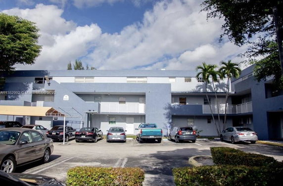 Front view of a multi-story residential building with parking area.