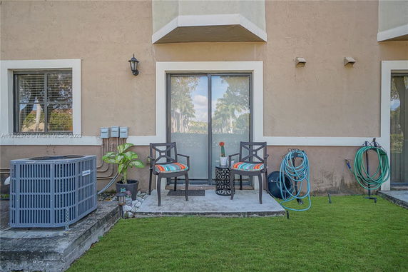 Front view of a building exterior with patio chairs and air conditioning unit.