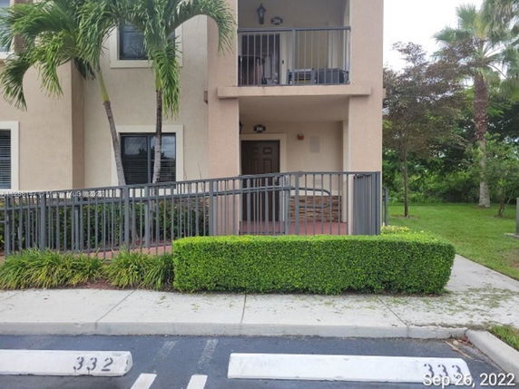Front view of a multi-story building with balconies and a ramp entrance.
