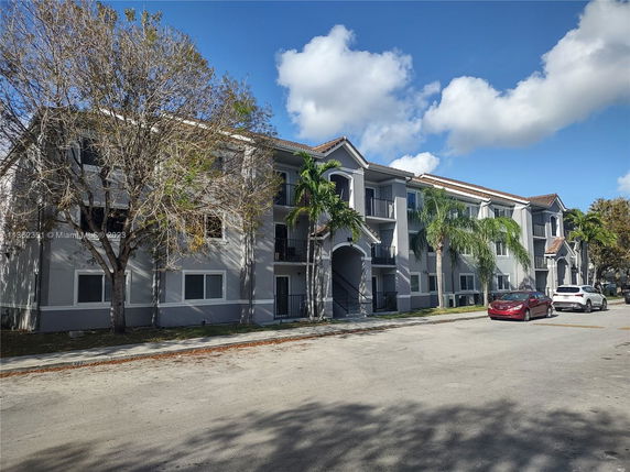 Front view of a multi-story residential building with a parking area in front.