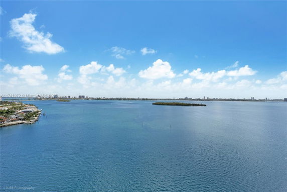 Wide-angle view of a large water body with city skyline in the distance and clear blue skies.