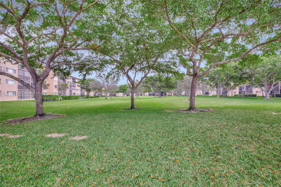 View of apartment buildings with trees and grass in the foreground.