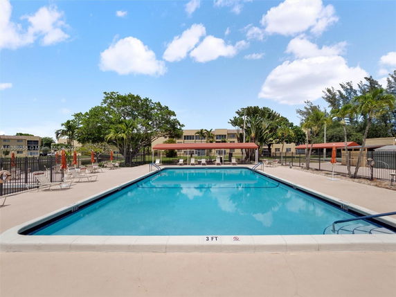 Outdoor swimming pool with sun loungers and umbrellas.