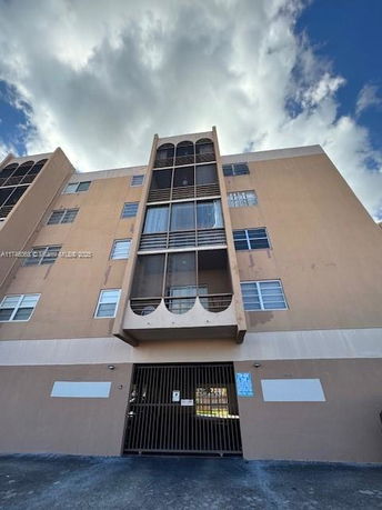Front view of a multi-story residential building with balconies and gated entrance.