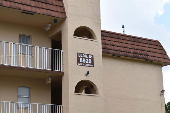 Front view of a multi-story building with balconies and a sign displaying BLDG. 81, 8920 Sunrise Lakes Blvd.
