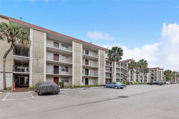 Front view of multi-story residential building with balconies and parking space.