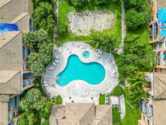 Aerial view of a swimming pool surrounded by residential buildings with lush greenery around.