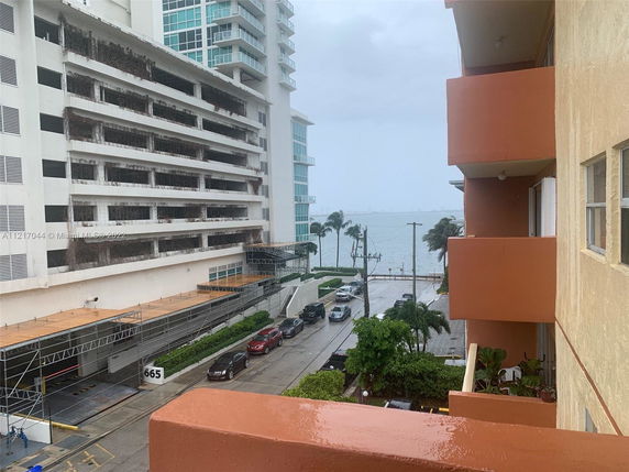 View of buildings and a street with cars, overlooking a body of water in the distance.