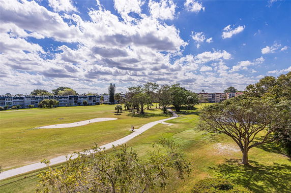 View of a grassy landscape with a golf course and residential buildings in the background.