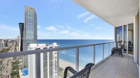 Panoramic view from a balcony overlooking the ocean and cityscape.