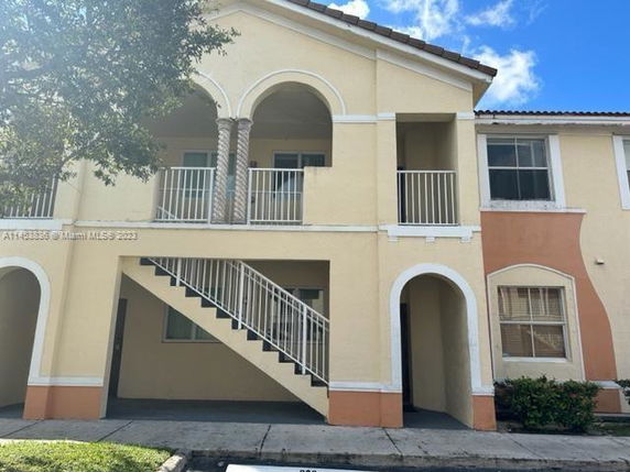 Front view of a two-story building with an external staircase and arch design.