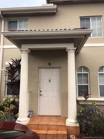 Front view of a two-story house with columns and a tiled entryway.