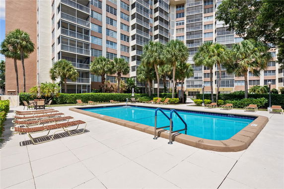 Exterior view of an apartment building with a swimming pool in the foreground.
