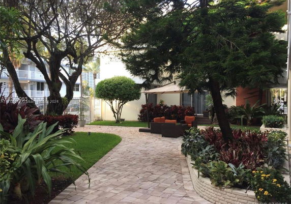 View of garden area with outdoor seating and pathway next to a building.