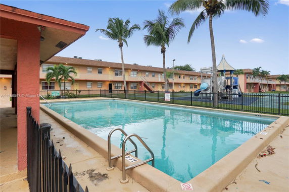 Outdoor swimming pool area with apartments in the background.