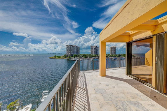 Terrace view from a building overlooking a body of water and distant high-rise buildings.