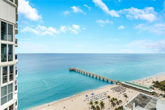Panoramic view of the ocean with a pier extending into the water, seen from a building.